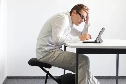 A man hunched over a tablet at a desk with poor sitting posture