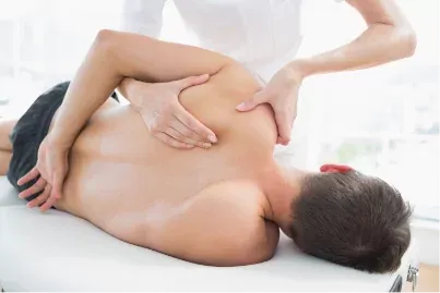 A therapist working on the shoulder blade of a patient lying on his side